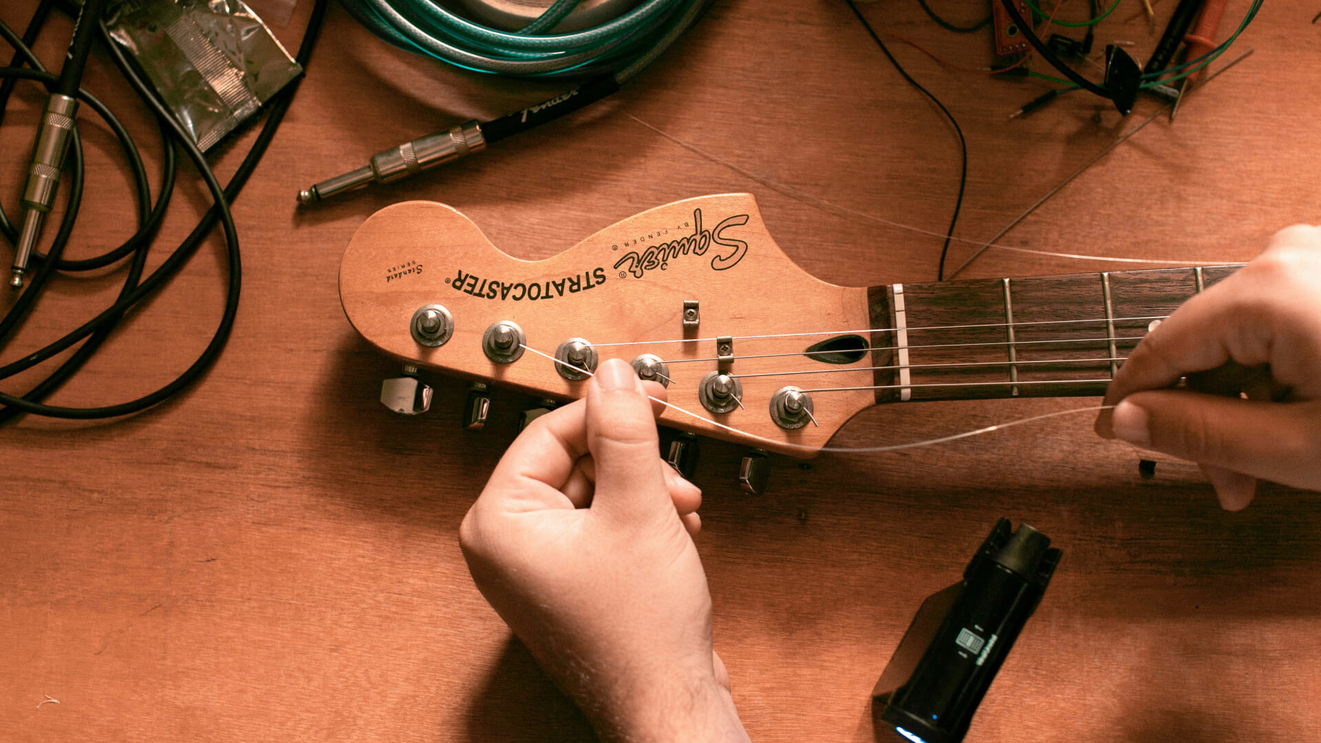 Person wechselt Gitarrensaiten