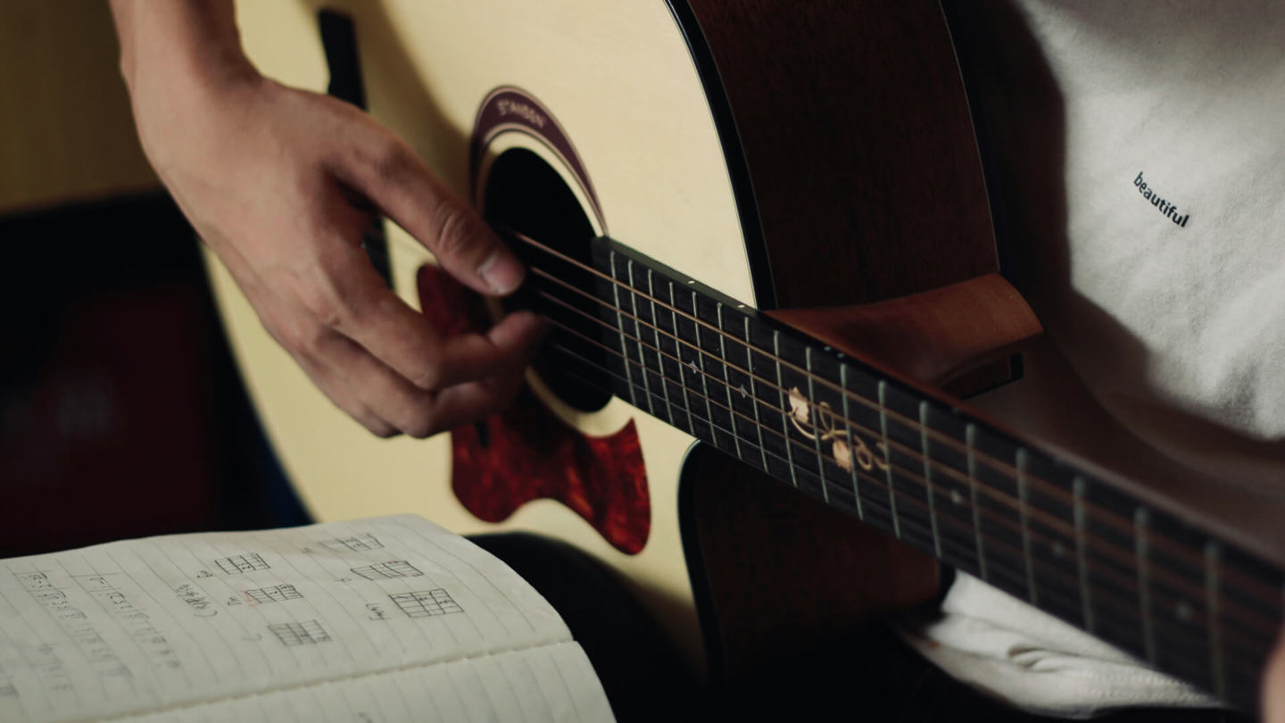 Person, die das Spielen auf einer akustischen Gitarre lernt